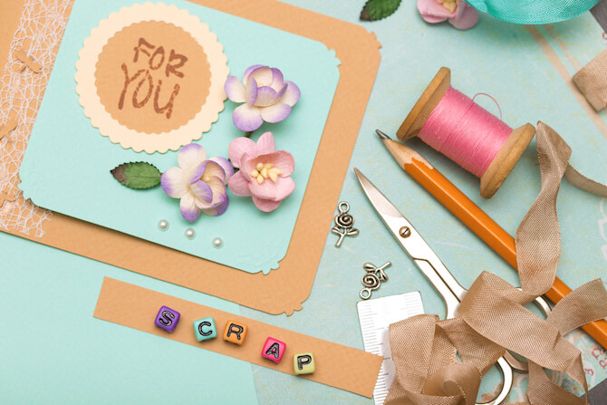 Tabletop with scrapbook materials that has beads spelling out Baby