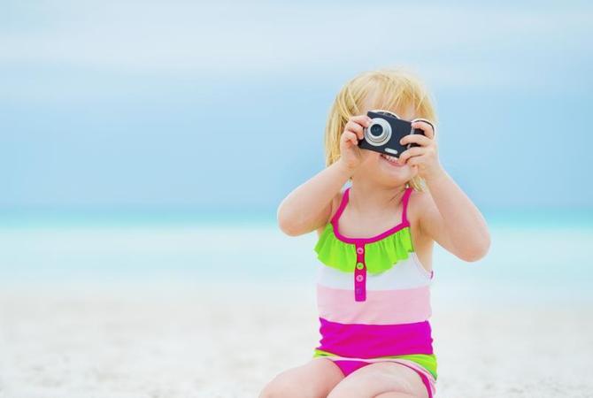 Baby with camera smiling and taking picture of you