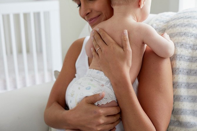 Mother holding her Huggies wearing baby