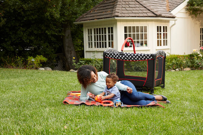 Child and mom playing on grass with baby toys