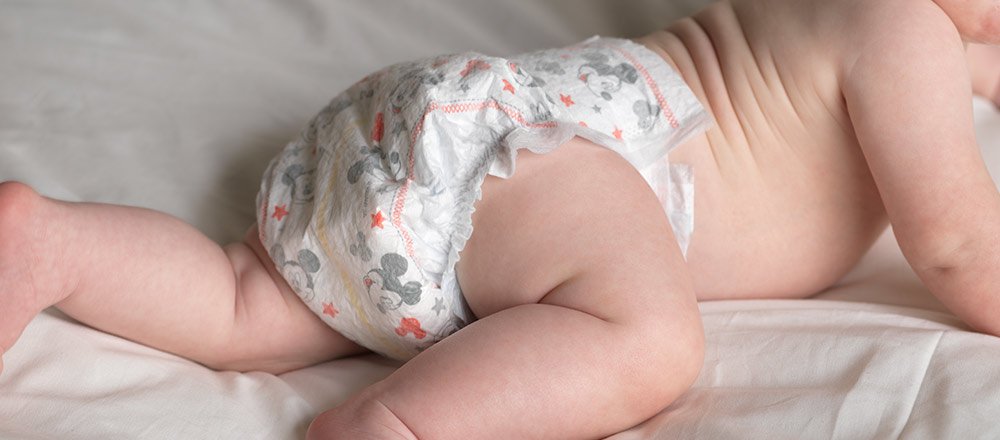 Un bébé est couché sur son ventre en portant une couche Snug and Dry de Huggies