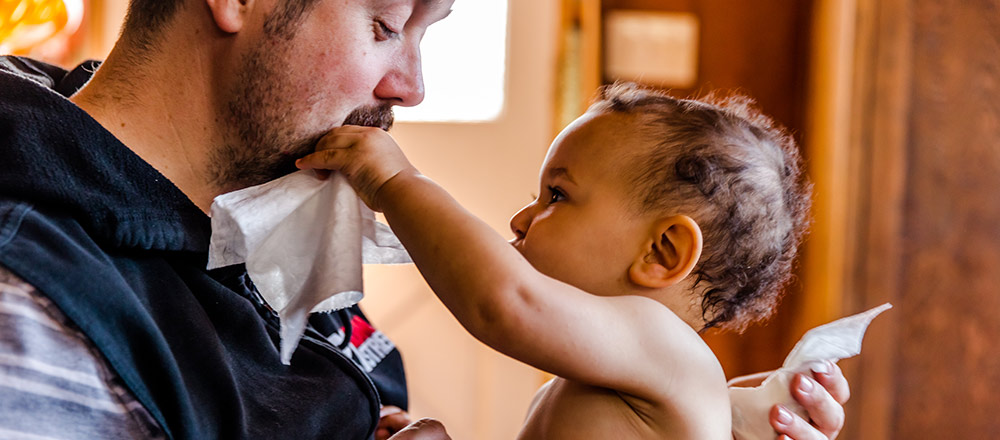 A baby reaches out to use a Huggies Nourish and Care Wipe on their father's face