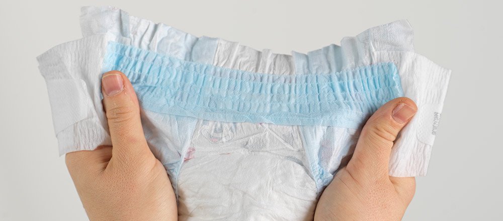 Hands holding a Huggies Snug and Dry Diaper showing its quilted liner