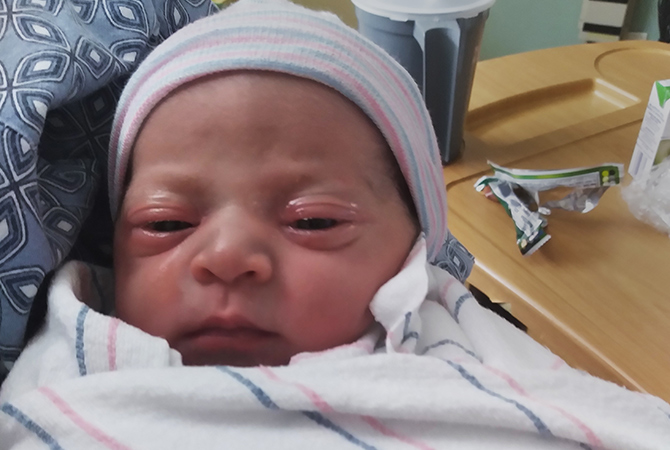 Newborn baby, Ashlyn, wrapped in a blanket with a beanie