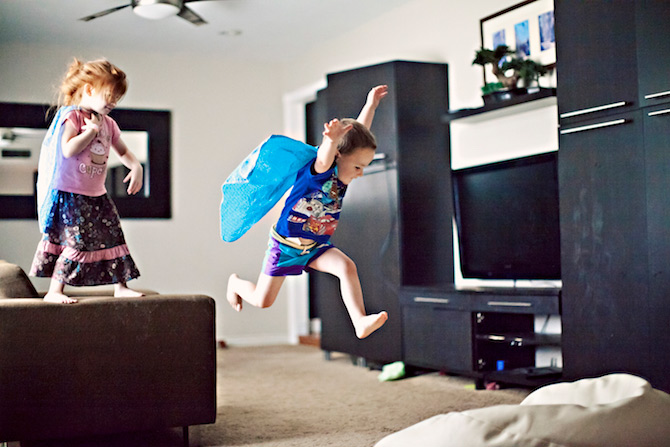 Kids running around living room playing super heroes