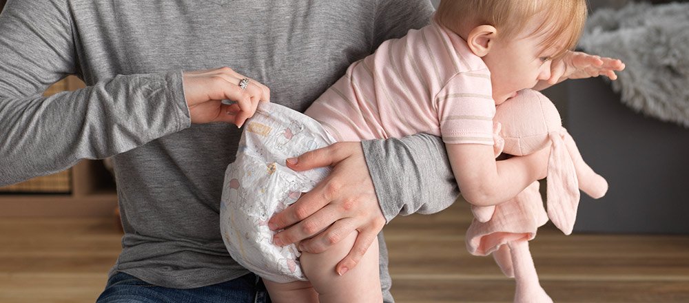 Un parent tient son bébé portant une couche Huggies Little&nbsp;Snugglers hypoallergénique et respirante