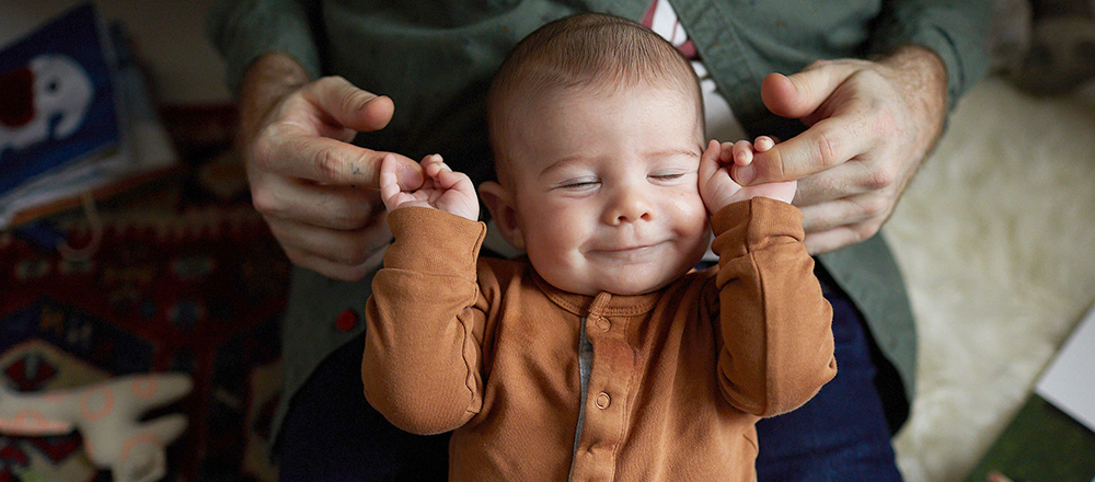 Un bébé souriant agrippe l'index de son père