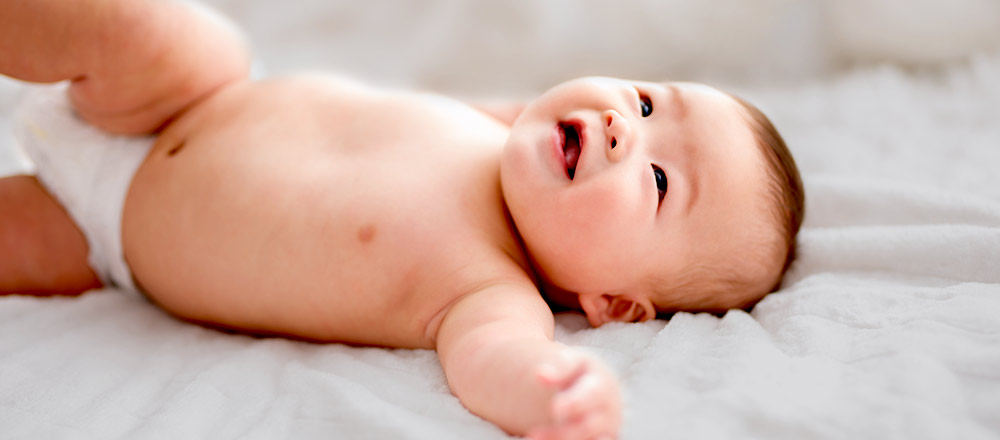 Un bebé con pañal sobre una manta blanca
