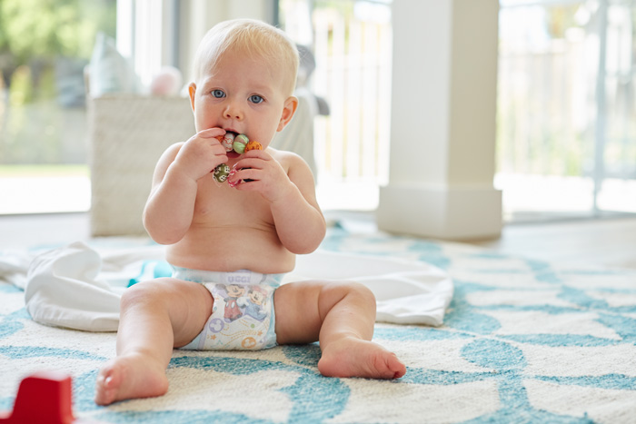 Baby in diaper chewing on a teething ring
