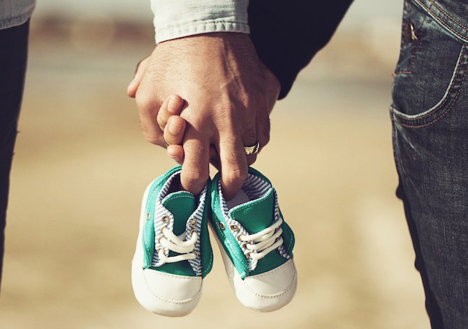 parents holding baby shoes