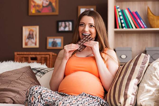 Pregnant woman eating a bar of chocolate