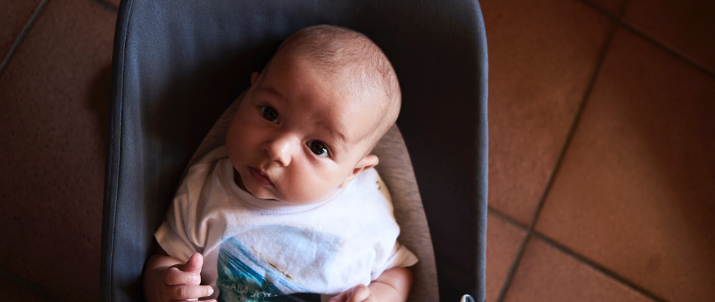 Un bebé curioso mira desde una silla azul