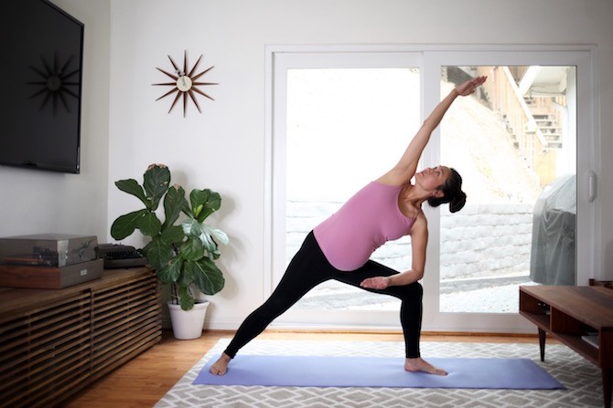 Pregnant woman doing yoga pose in sun lit room