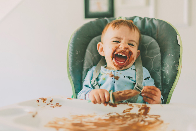 Messy baby eating in a baby chair